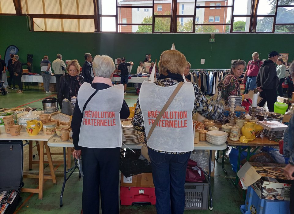 Deux bénévoles porte les chasubles aux couleurs du Secours Catholique
